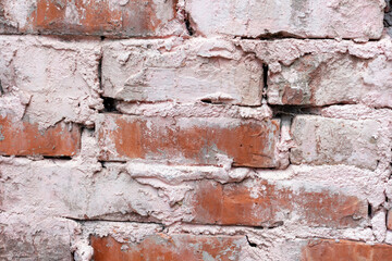 Textured old brick wall background. Close-up view of weathered pink paint over red brick wall surface covered with spots and streaks. Copy space for your text and decorations. Abstract backdrop theme.