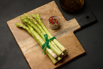 Fresh green asparagus sprouts on a black wooden background. View from above