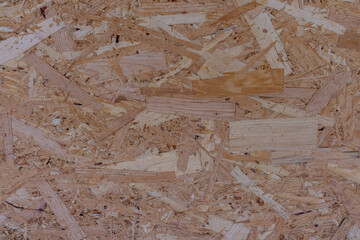 Abstract brown wooden particle board (particleboard, chipboard, or low-density fiberboard) background. Close-up view of recycled compressed wood chippings board surface. Construction material theme.