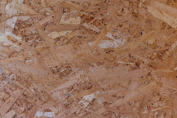 Abstract brown wooden particle board (particleboard, chipboard, or low-density fiberboard) background. Close-up view of recycled compressed wood chippings board surface. Construction material theme.