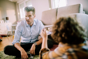 Father posing for picture with funny face taken by son at home