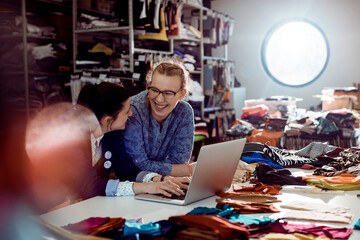 Two women fashion designers collaborating over a laptop in a creative studio