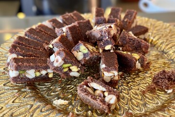 The portions of chocolate cake with nuts on a golden stand on the counter of the restaurant. Close-up