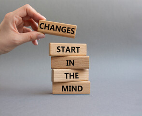 Changes start in the Mind symbol. Wooden blocks with words Changes start in the Mind. Beautiful grey background. Businessman hand. Business and Changes start in the Mind concept. Copy space.