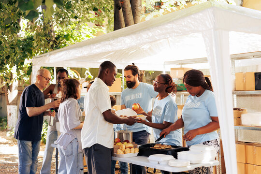 Multiethnic group of individuals collaborate at charity center, organizing a food drive to support the poor and needy. The selfless actions of volunteers provides hunger relief and humanitarian aid.