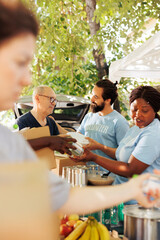 Multiracial humanitarian aid team combats hunger and poverty by providing donation boxes to the...