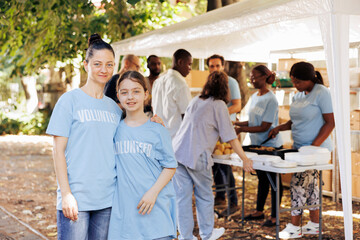 Portrait shot of a mother and daughter, supporting hunger relief initiative at an outdoor food...