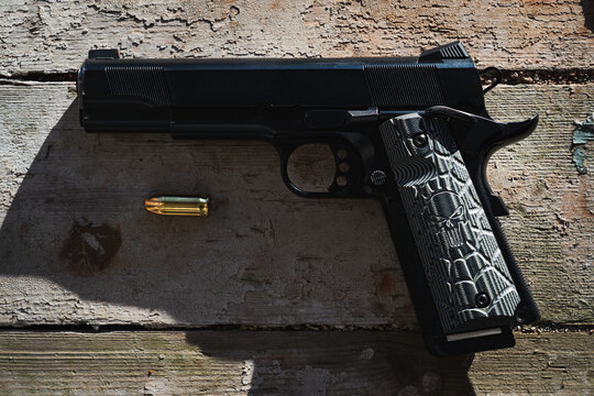 American classic brutal pistol m1911 on a wooden window sill of an abandoned building.