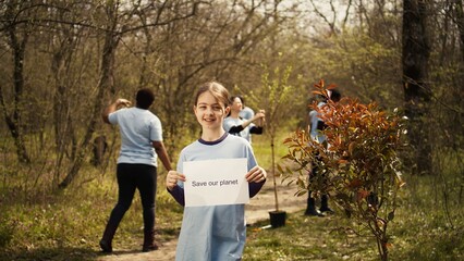 Portrait of sweet girl with save our planet poster against pollution and illegal dumping,...