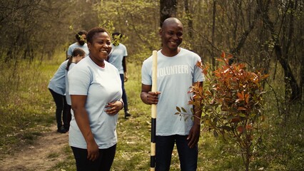 Portrait of a couple volunteering to plant trees and collect trash from the woods, hold shovel and...