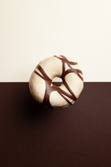 A chocolate and vanilla donut with a brown center. The donut is sitting on a dark brown background