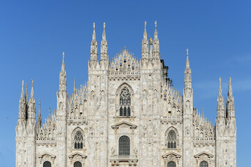 Top front gable of Milan duomo, one of the biggest roman catholic cathedrals in the world, with clear blue sky