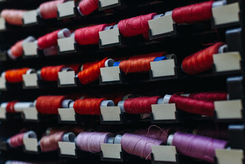 amount of different skeins of threads on special shelves in sewing studio or atelier, several...