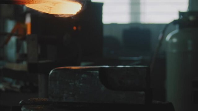 Blacksmith placing and hammering smelted metal on an anvil