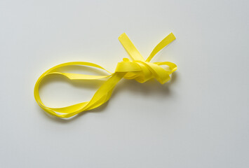 isolated yellow ribbon loosely knotted on blank paper