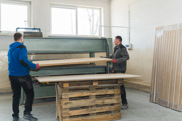 carpenters working on the wooden panel at the factory, belt grinder machine. High quality photo