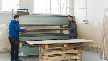 workers sliding a wooden panel in the belt grinder, workshop. High quality photo