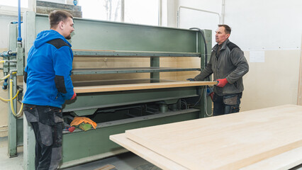 carpenters sliding in wooden panel in belt grinder, craftsmen. High quality photo