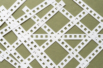 blank white paper binding strips arranged in a loose grid pattern on green
