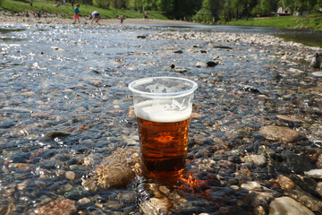 A cup of beer set up in the water in the river