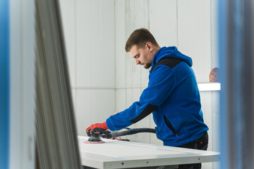 Naklejka na ściany i meble Male carpenter using orbital electric sander in a workshop. High quality photo