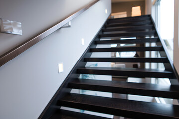 Fototapeta premium Modern black stairs with sleek wooden handrail, minimalist interior design.