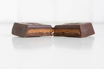dark chocolate with hazelnut butter filling on white background, shown in cross section, close up macro with shallow depth of field and copy space
