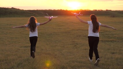 Dreams of flying. Happy childhood concept. Two girls play with a toy plane at sunset. Children on...