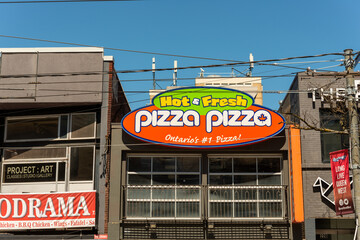 Obraz premium exterior sign of Pizza Pizza, chain restaurant that sells baked dough with topping and other fast food items, located here at 228 Queen Street West in Toronto, ON