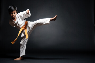 Latin boy doing Karate exercises. The leg raised to 90 degrees.