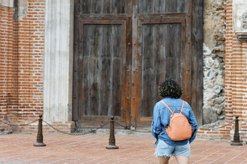 Mujer joven caminando hacia la entrada de una iglesia antigua en la ciudad de Antigua Guatemala.