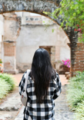 Mujer hispana caminando por los jardines en las ruinas en una ciudad colonial. Toma Vertical.