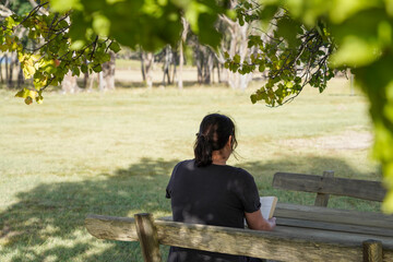 Woman reading a book on a wooden bench