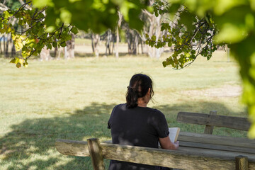 Fototapeta premium Woman reading a book on a wooden bench