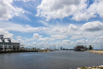 The Southern Yacht Club with ocean water, lush green trees and grass, boats and yachts, blue sky and clouds in New Orleans Louisiana USA