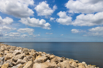 a gorgeous spring landscape at Breakwater Park with ocean water, rocks, blue sky and clouds in New...