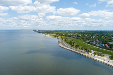 aerial shot along the coast of Lake Pontchartrain with homes, lush green trees, plants and grass,...
