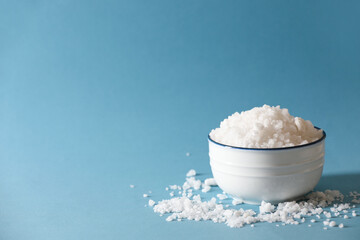 Organic salt in bowl on light blue background. Space for text