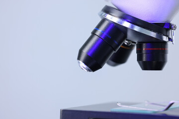Modern microscope on light background, closeup view. Space for text