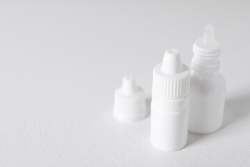 Bottles of medical drops on white background, space for text