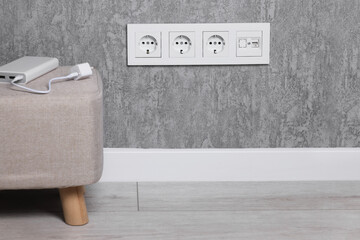 Electric power sockets on grey wall indoors, space for text