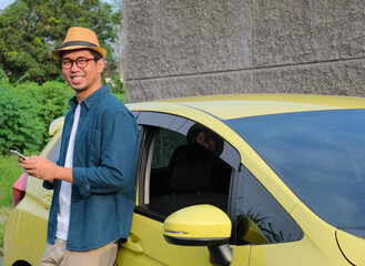 A man standing beside his car smiling happy while holding mobile phone