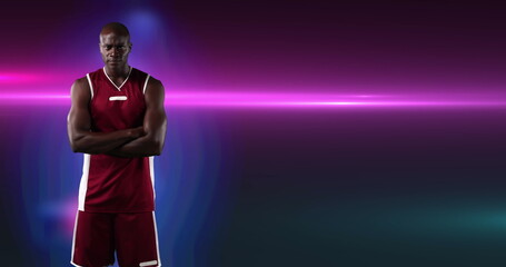 Image of african american male basketball player with arms crossed on purple background