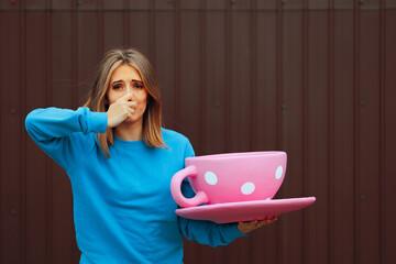Woman Holding a Huge Cup of Coffee Disliking its Aroma. Unhappy girl feeling unhappy about the...