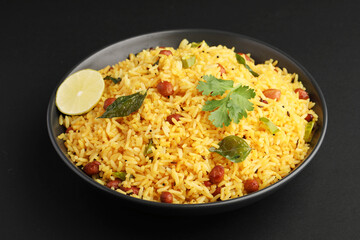 Lemon Rice or fodnicha bhat is South Indian turmeric rice or maharashtrian recipe using leftover rice garnished with nuts curry leaves and lemon juice, selective focus