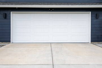 New white paneled garage door on house painted navy blue, cement driveway
