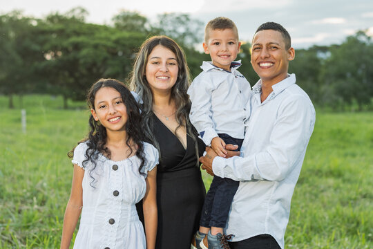 Colombian Latino family, smiling very happy, daughter, mother, father and son posing in the countryside.