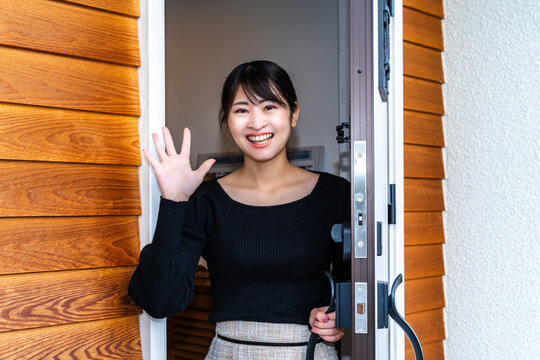 玄関で手を振る若い女性