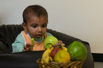 A baby trying to pick fruits. Eating, healthy, bowl, spoon, curious, happy, mother, boy, girl,...