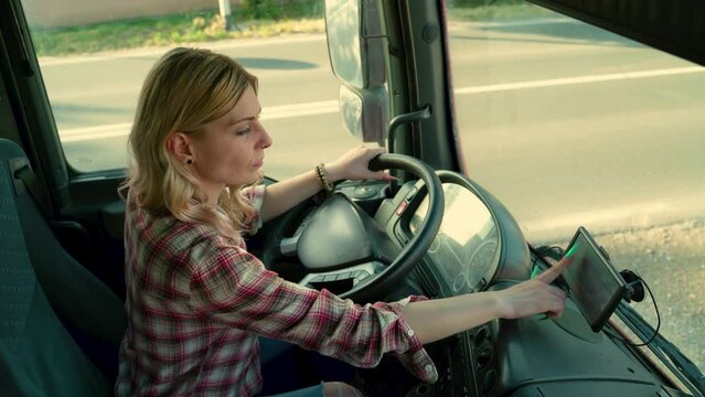 Young blonde girl truck driver entering data in navigation  before trip